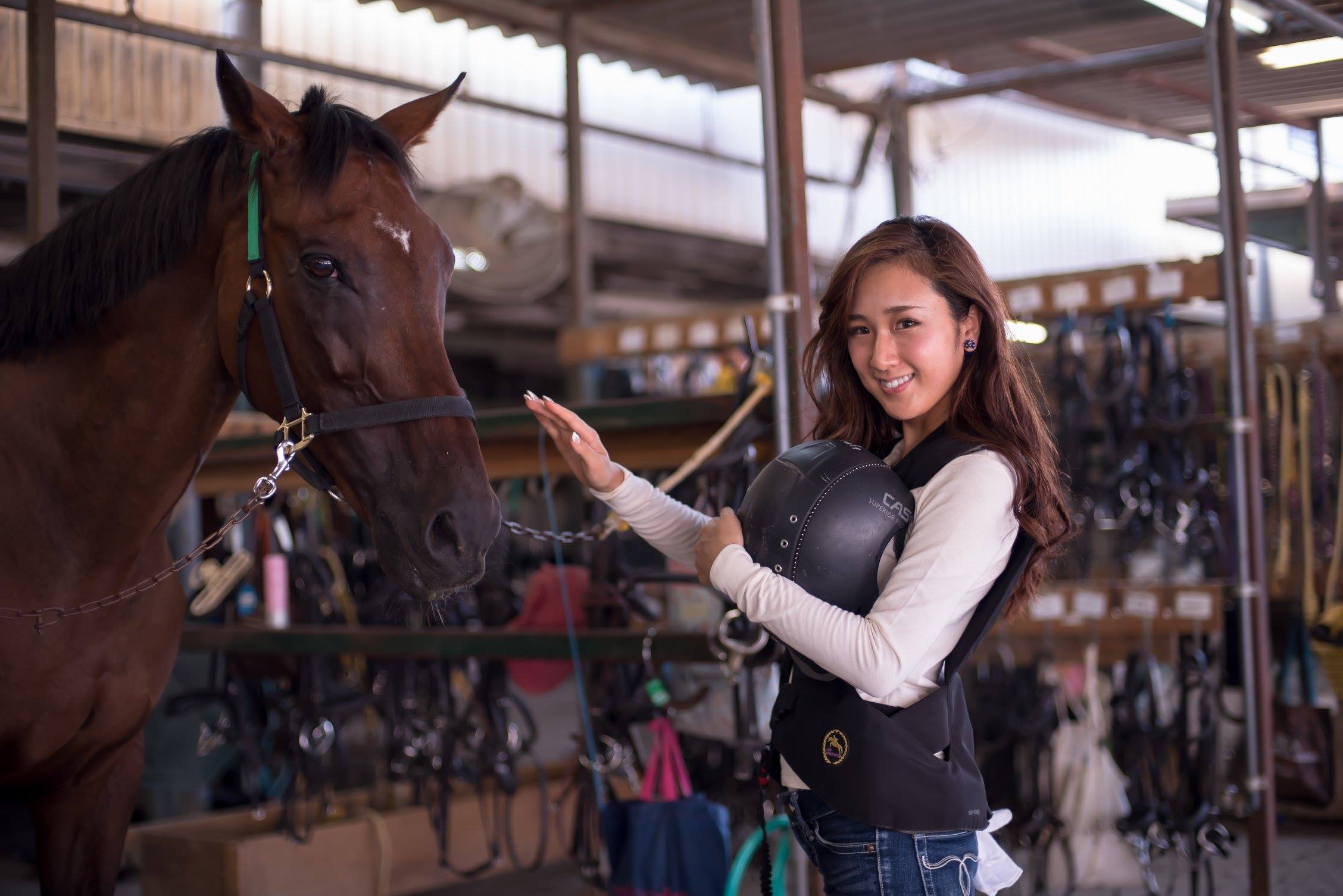 厩舎で馬とふれあう女性